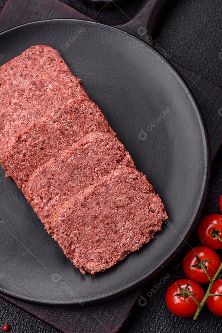 Delicioso presunto rosa enlatado com sal, especiarias e ervas sobre um fundo escuro de concreto