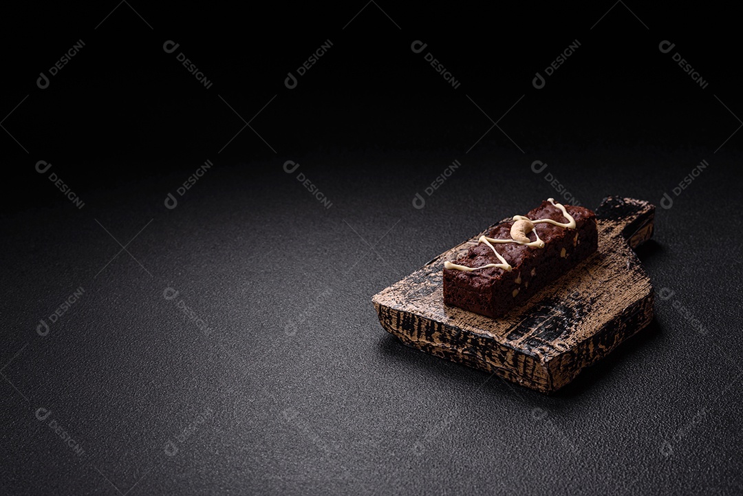 Deliciosos brownies doces com chocolate e nozes em um fundo escuro de concreto