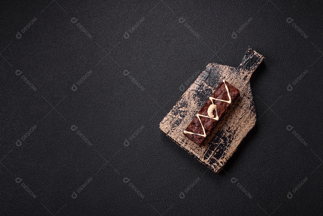 Deliciosos brownies doces com chocolate e nozes em um fundo escuro de concreto