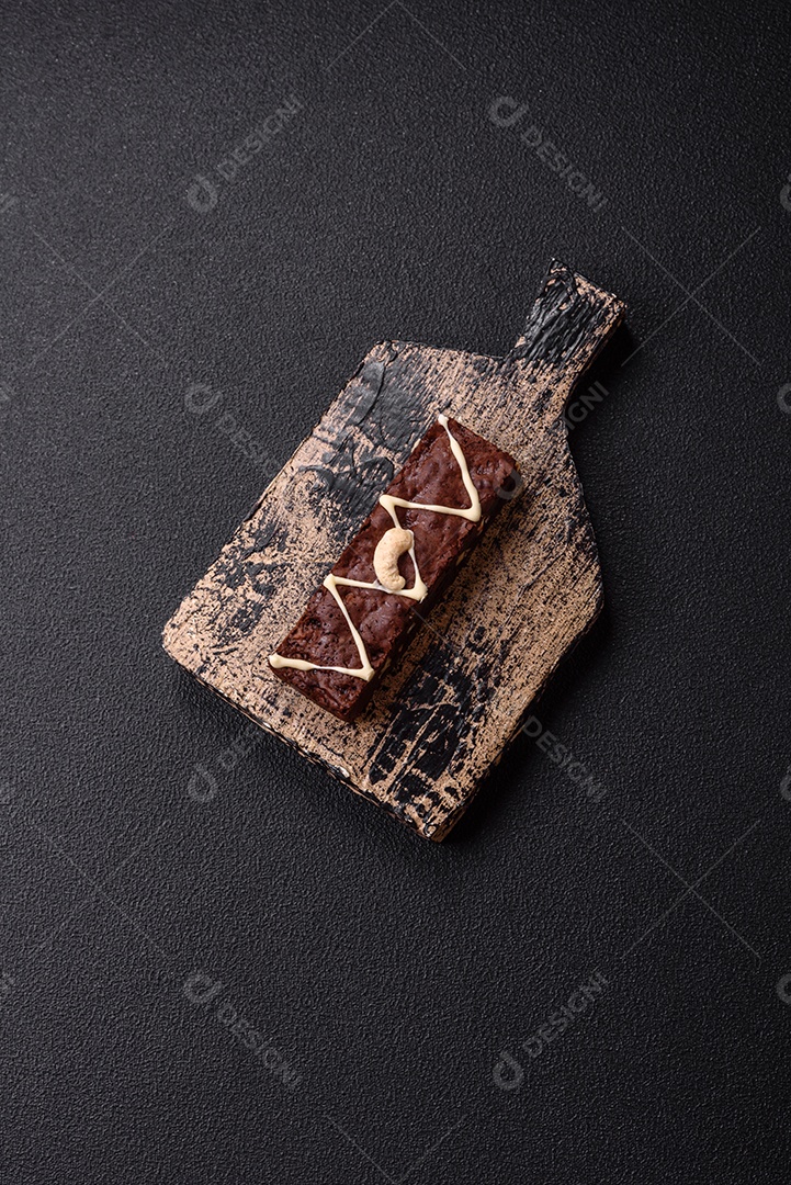Deliciosos brownies doces com chocolate e nozes em um fundo escuro de concreto