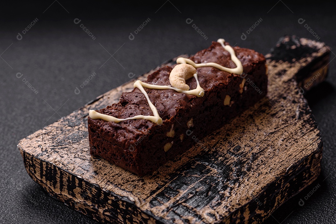 Deliciosos brownies doces com chocolate e nozes em um fundo escuro de concreto