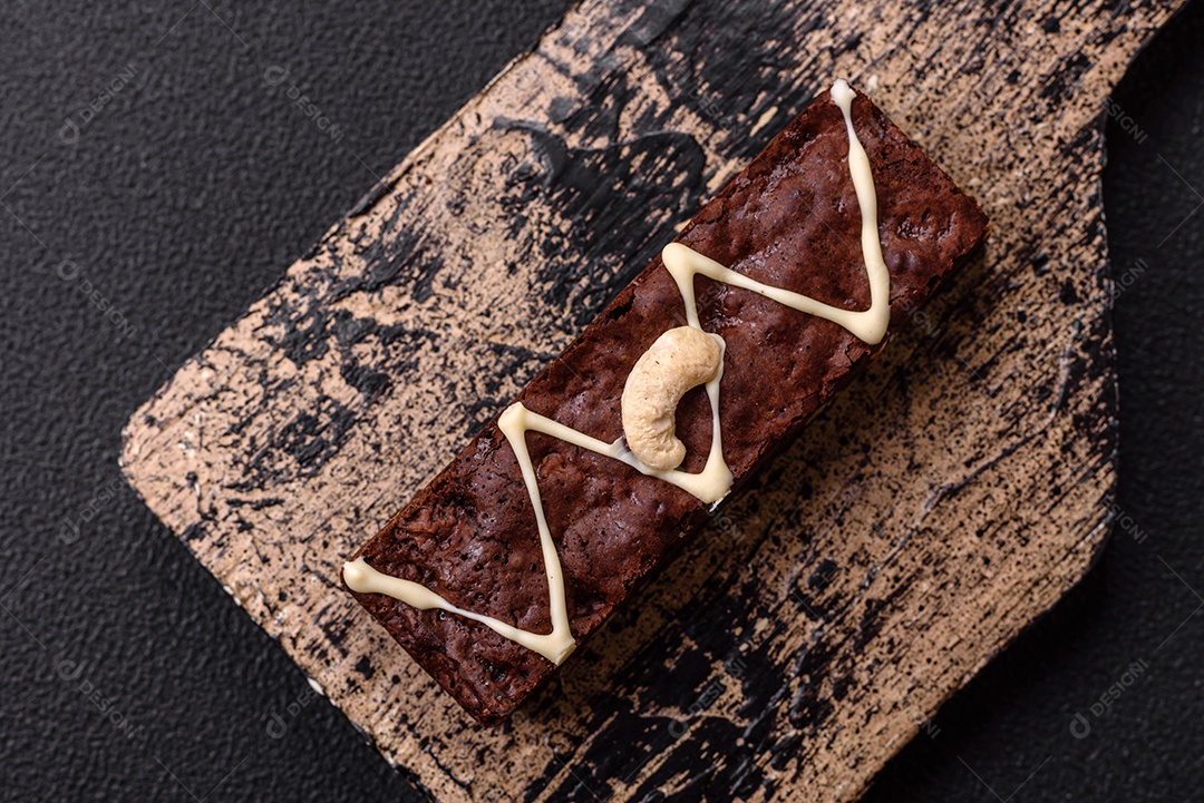 Deliciosos brownies doces com chocolate e nozes em um fundo escuro de concreto