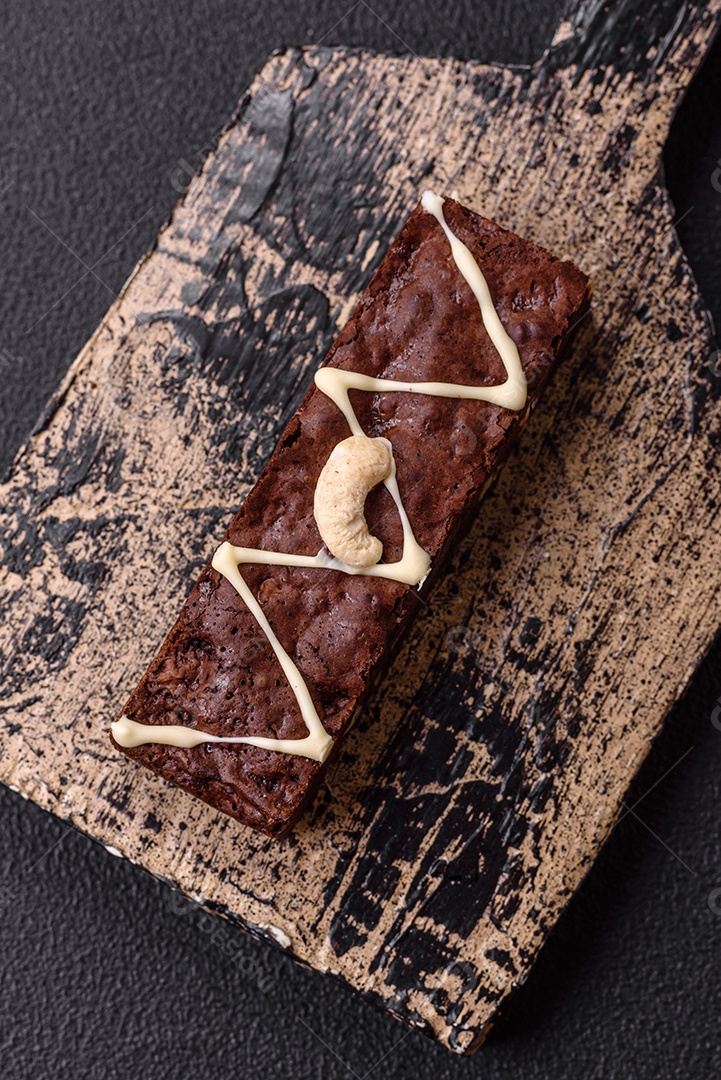 Deliciosos brownies doces com chocolate e nozes em um fundo escuro de concret