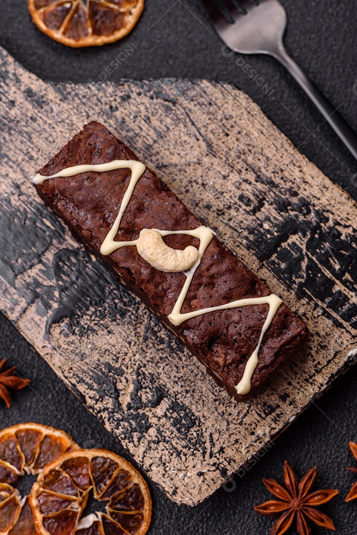 Deliciosos brownies doces com chocolate e nozes em um fundo escuro de concreto