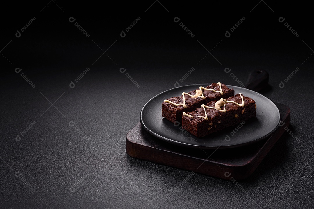 Deliciosos brownies doces com chocolate e nozes em um fundo escuro de concreto