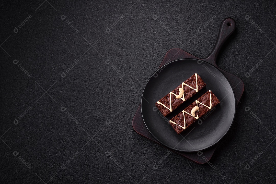 Deliciosos brownies doces com chocolate e nozes em um fundo escuro de concreto