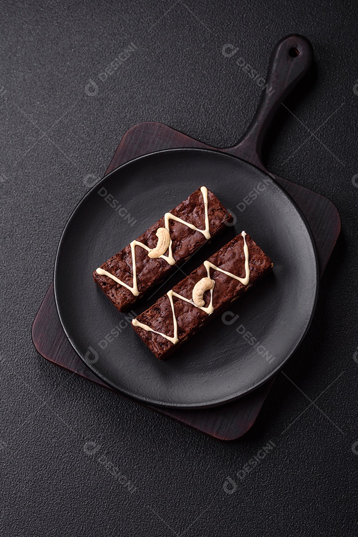 Deliciosos brownies doces com chocolate e nozes em um fundo escuro de concreto