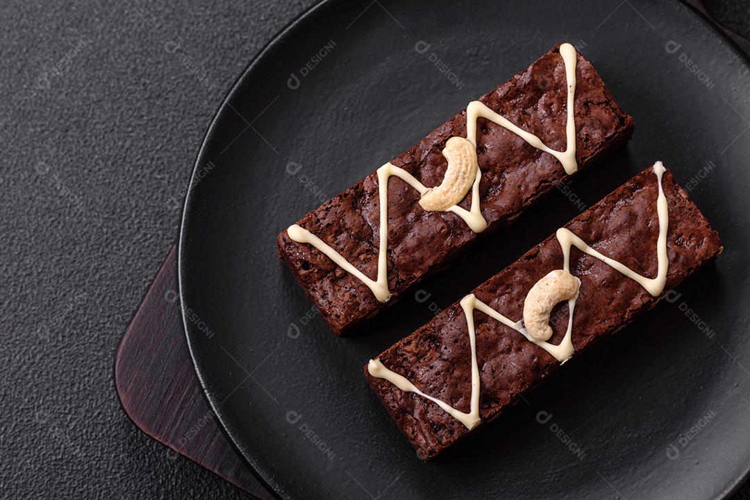 Deliciosos brownies doces com chocolate e nozes em um fundo escuro de concreto