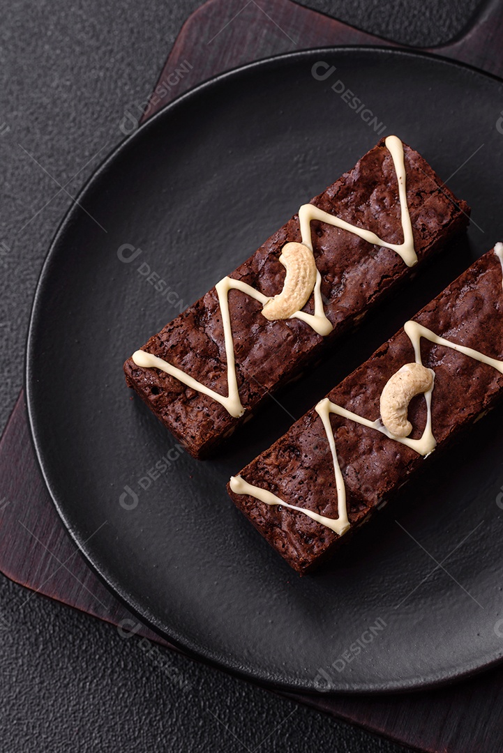 Deliciosos brownies doces com chocolate e nozes em um fundo escuro de concreto