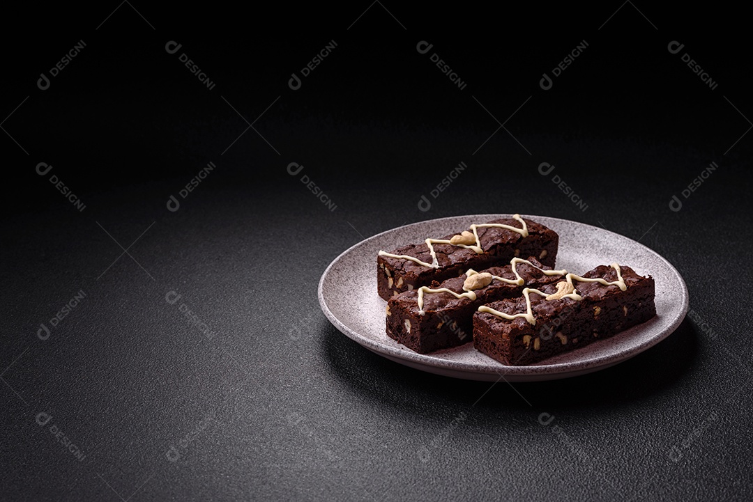 Deliciosos brownies doces com chocolate e nozes em um fundo escuro de concreto