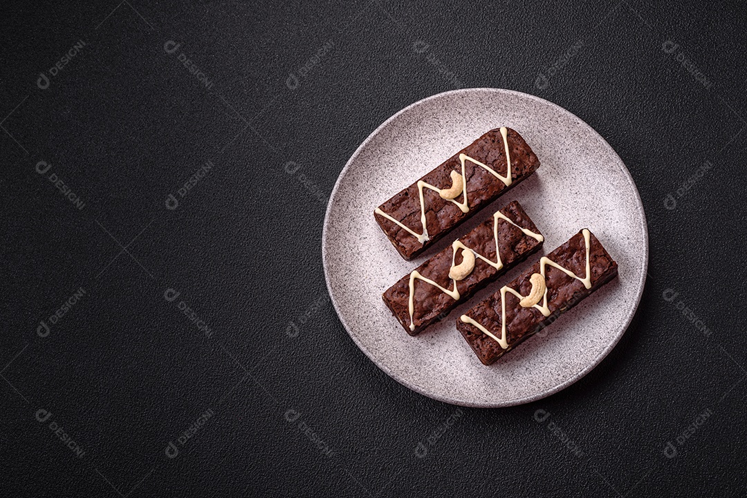 Deliciosos brownies doces com chocolate e nozes em um fundo escuro de concreto