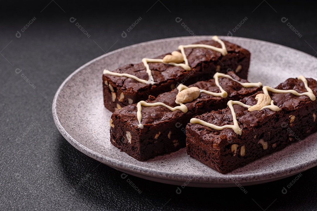 Deliciosos brownies doces com chocolate e nozes em um fundo escuro de concreto