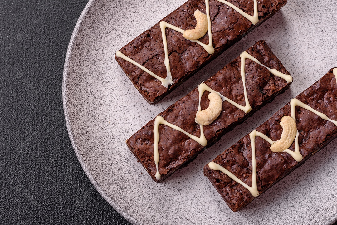 Deliciosos brownies doces com chocolate e nozes em um fundo escuro de concreto