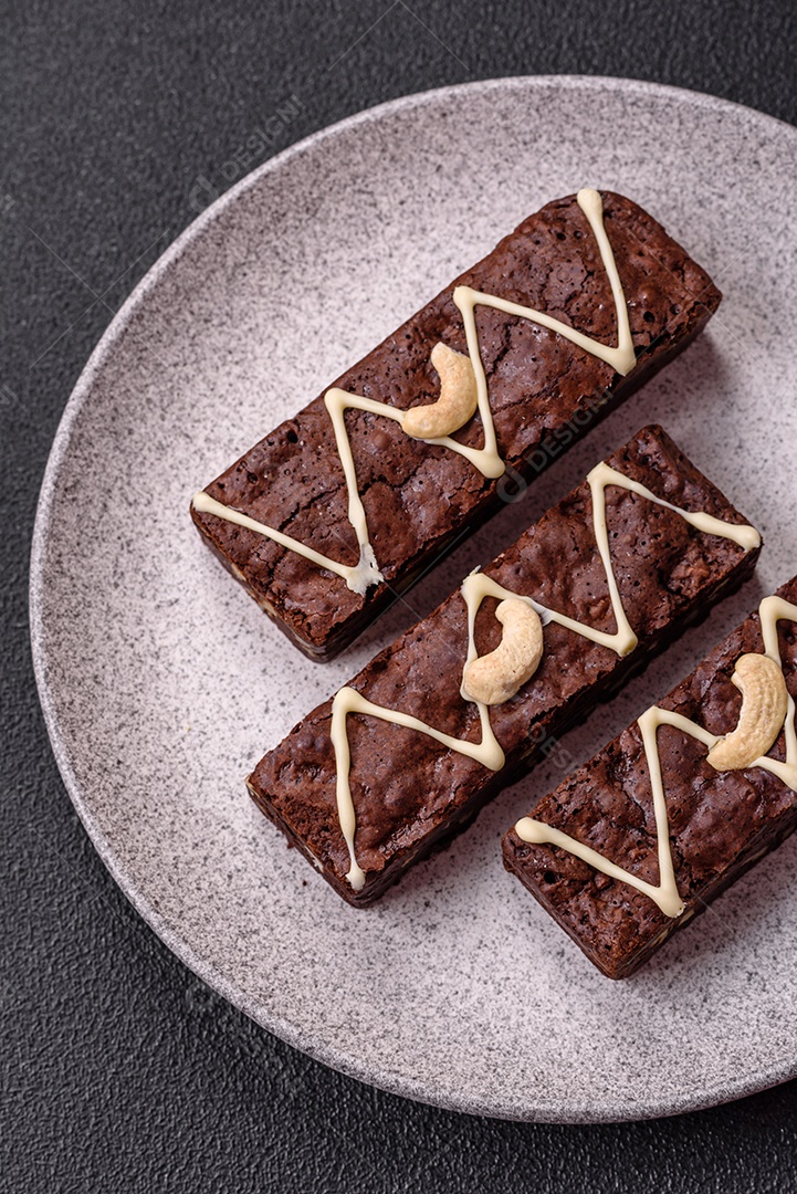 Deliciosos brownies doces com chocolate e nozes em um fundo escuro de concreto