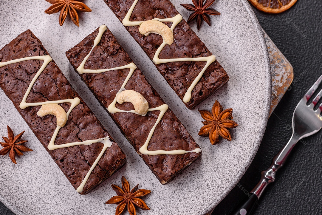 Deliciosos brownies doces com chocolate e nozes em um fundo escuro de concreto