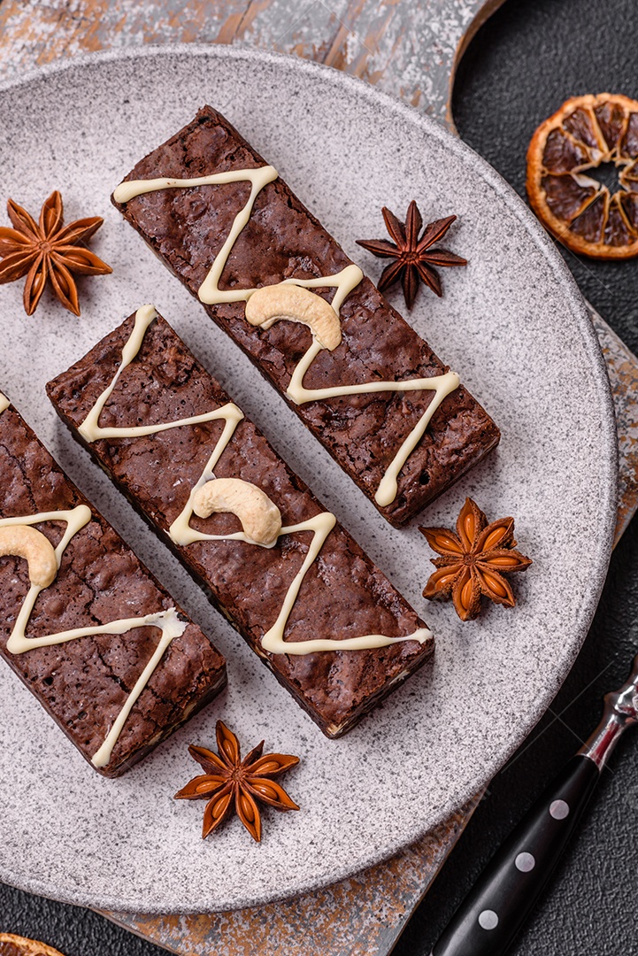 Deliciosos brownies doces com chocolate e nozes em um fundo escuro de concreto