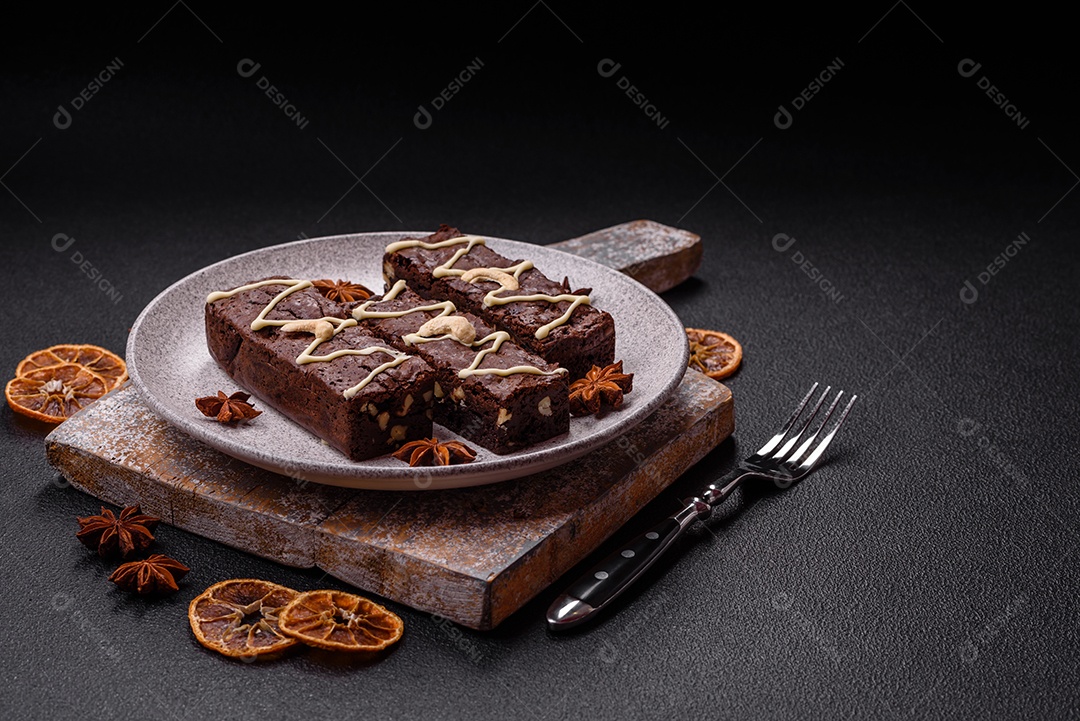 Deliciosos brownies doces com chocolate e nozes em um fundo escuro de concreto