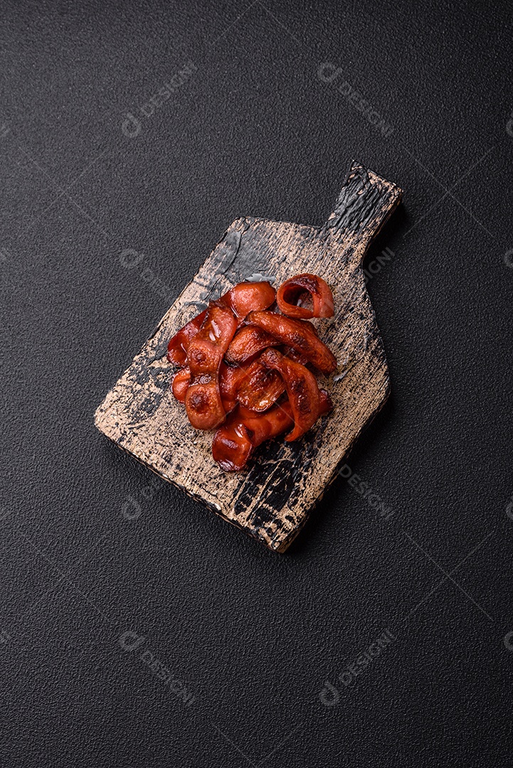 Salsichas fritas cortadas com sal e especiarias como ingrediente para um café da manhã inglês sobre fundo escuro de concreto