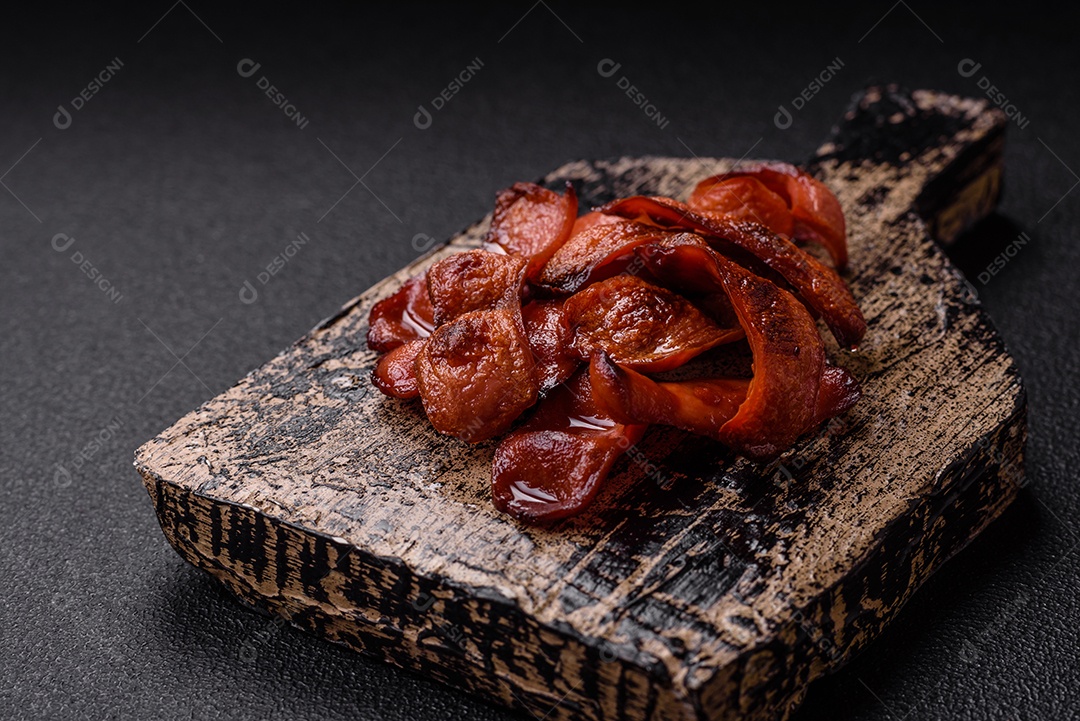 Salsichas fritas cortadas com sal e especiarias como ingrediente para um café da manhã inglês sobre fundo escuro de concreto
