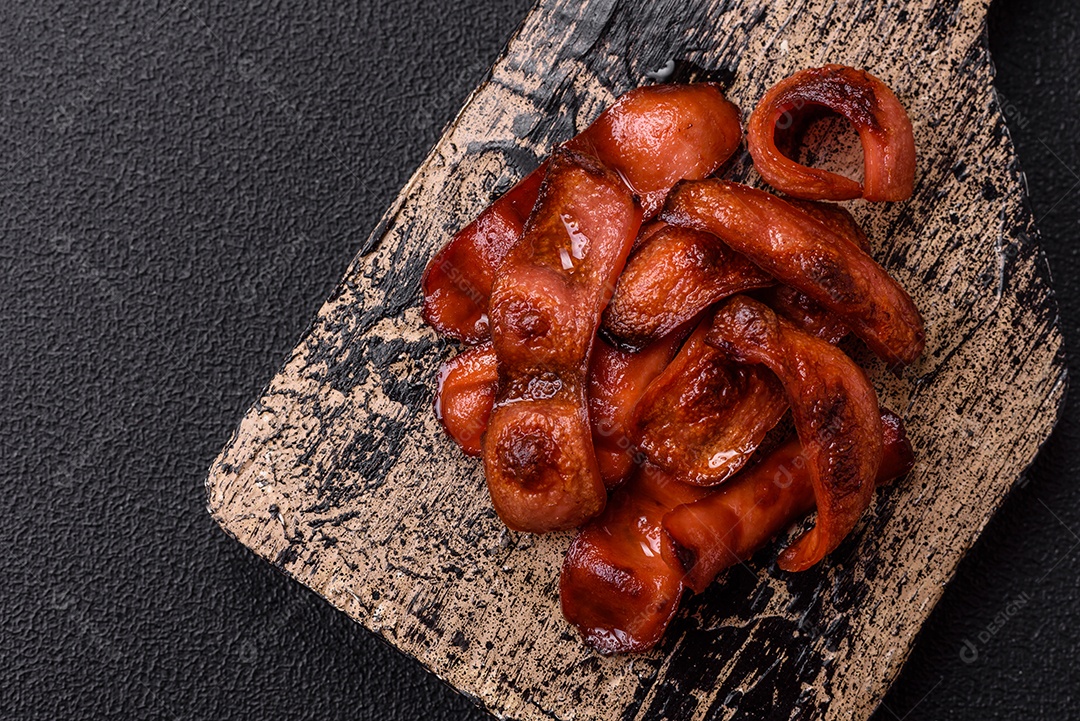 Salsichas fritas cortadas com sal e especiarias como ingrediente para um café da manhã inglês sobre fundo escuro de concreto