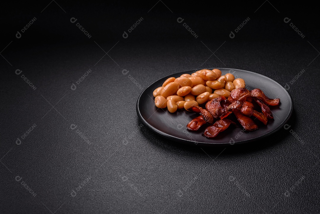 Delicioso feijão enlatado nutritivo com tomate, com sal e temperos como complemento de alto teor calórico para o café da manhã