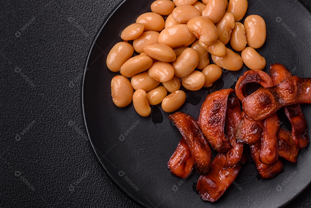 Delicioso feijão enlatado nutritivo com tomate, com sal e temperos como complemento de alto teor calórico para o café da manhã