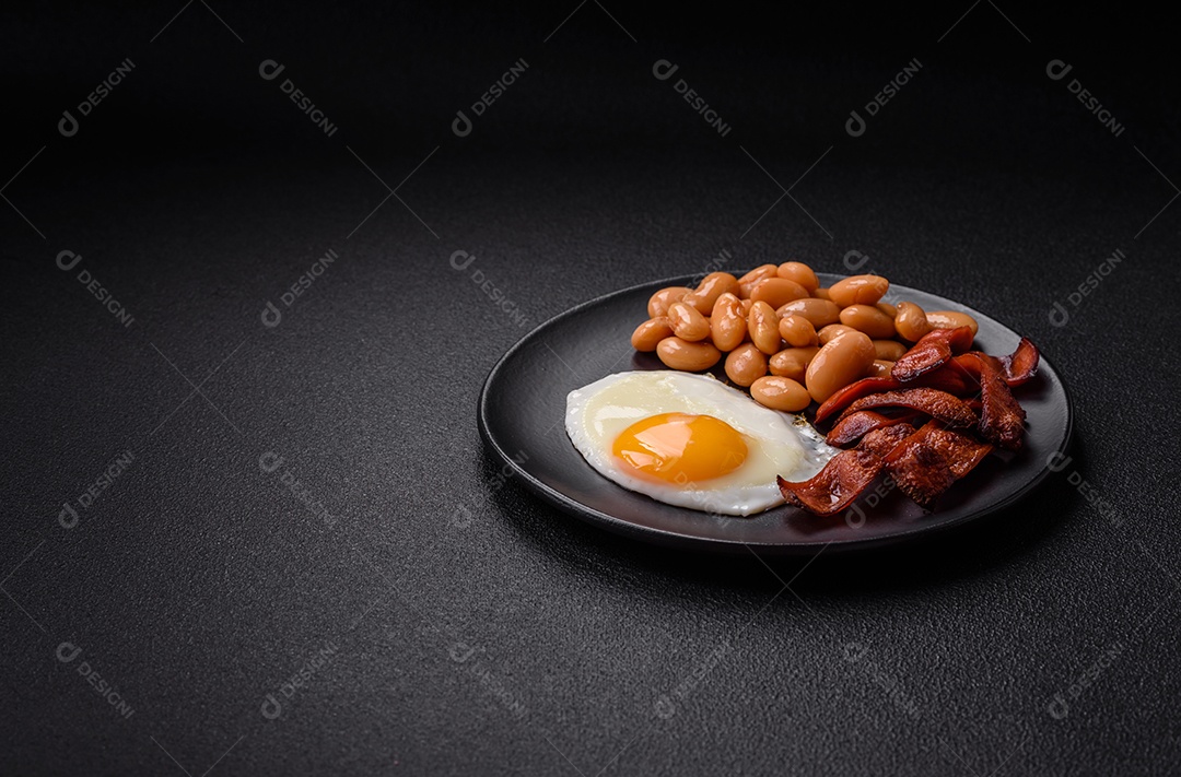 Café da manhã inglês com ovos fritos, bacon, feijão, tomate, especiarias e ervas. Um início de dia saudável e nutritivo