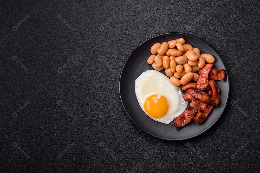 Café da manhã inglês com ovos fritos, bacon, feijão, tomate, especiarias e ervas. Um início de dia saudável e nutritivo