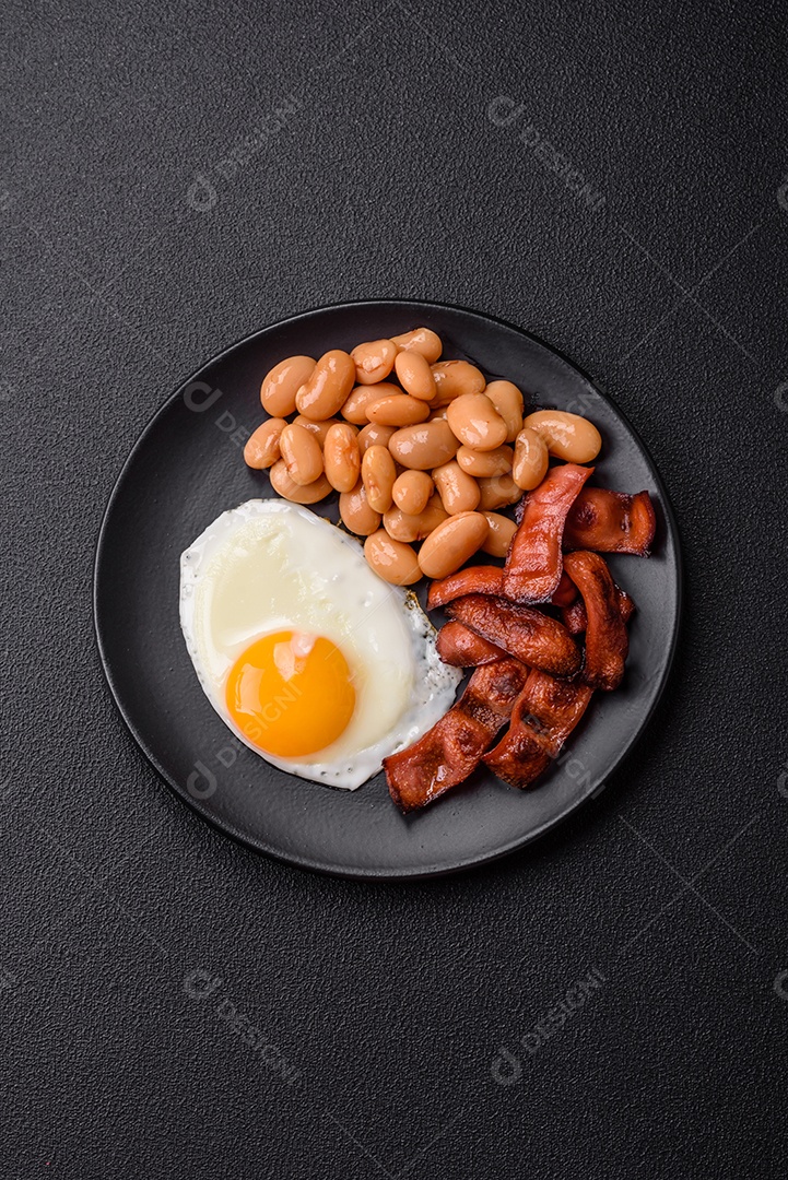 Café da manhã inglês com ovos fritos, bacon, feijão, tomate, especiarias e ervas. Um início de dia saudável e nutritivo