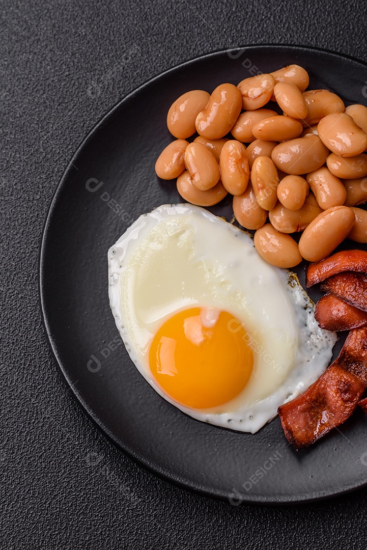 Café da manhã inglês com ovos fritos, bacon, feijão, tomate, especiarias e ervas. Um início de dia saudável e nutritivo