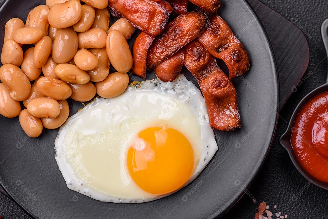 Café da manhã inglês com ovos fritos, bacon, feijão, tomate, especiarias e ervas. Um início de dia saudável e nutritivo