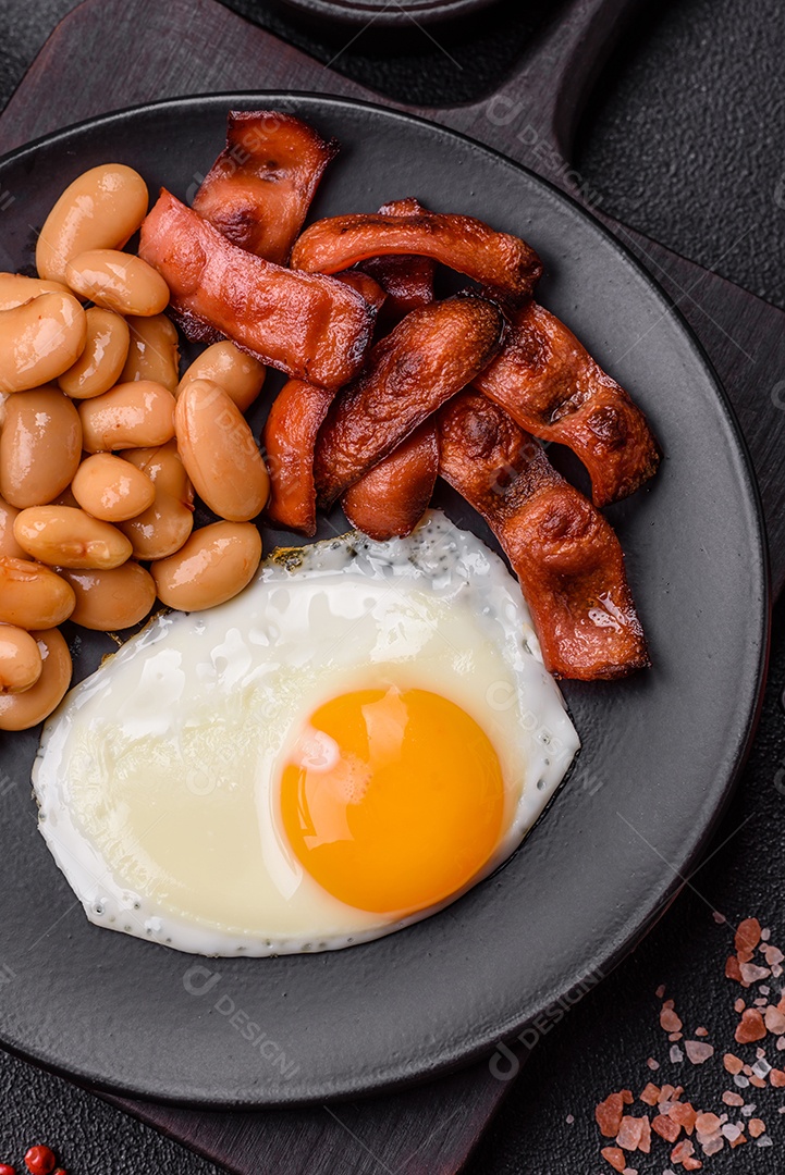 Café da manhã inglês com ovos fritos, bacon, feijão, tomate, especiarias e ervas. Um início de dia saudável e nutritivo