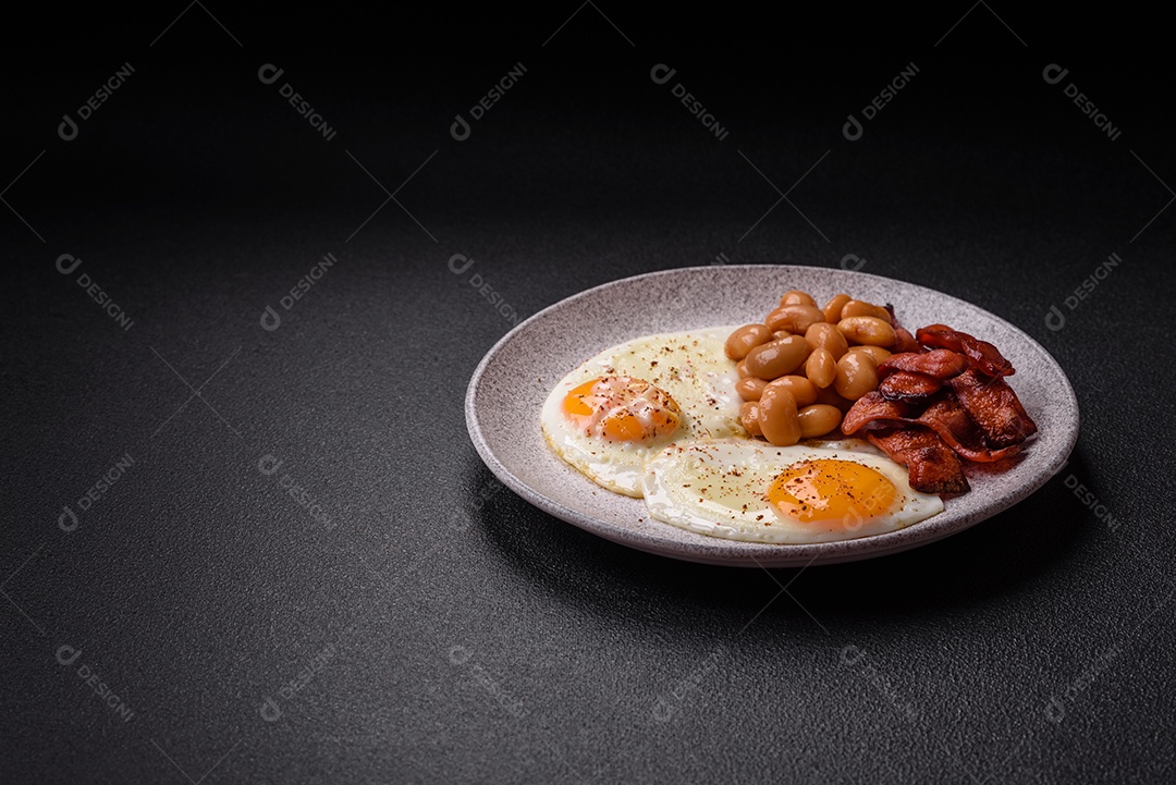 Café da manhã inglês com ovos fritos, bacon, feijão, tomate, especiarias e ervas. Um início de dia saudável e nutritivo