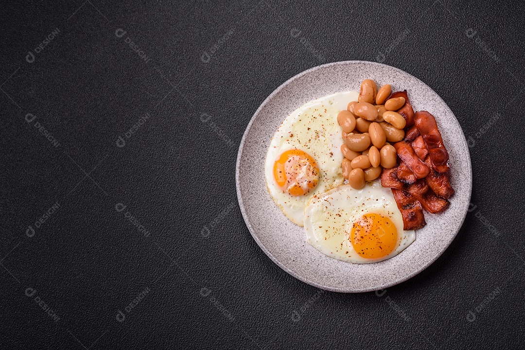 Café da manhã inglês com ovos fritos, bacon, feijão, tomate, especiarias e ervas. Um início de dia saudável e nutritivo