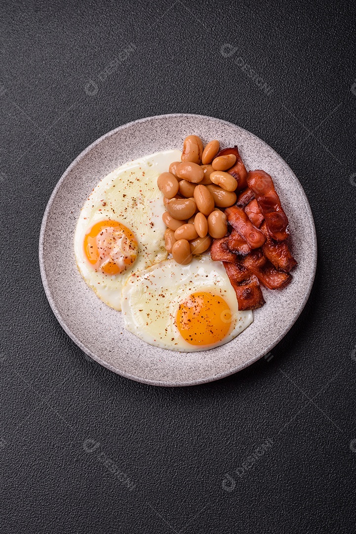 Café da manhã inglês com ovos fritos, bacon, feijão, tomate, especiarias e ervas. Um início de dia saudável e nutritivo