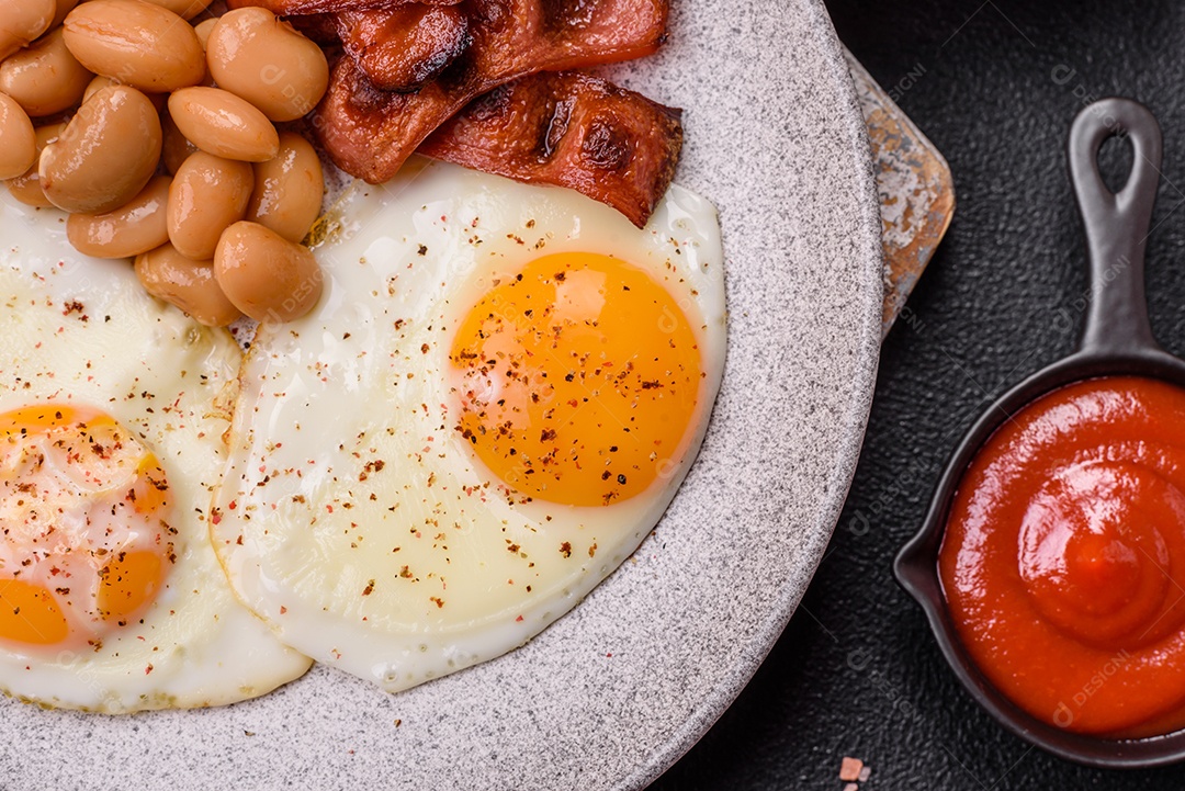 Café da manhã inglês com ovos fritos, bacon, feijão, tomate, especiarias e ervas. Um início de dia saudável e nutritivo