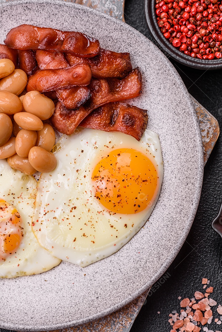 Café da manhã inglês com ovos fritos, bacon, feijão, tomate, especiarias e ervas. Um início de dia saudável e nutritivo