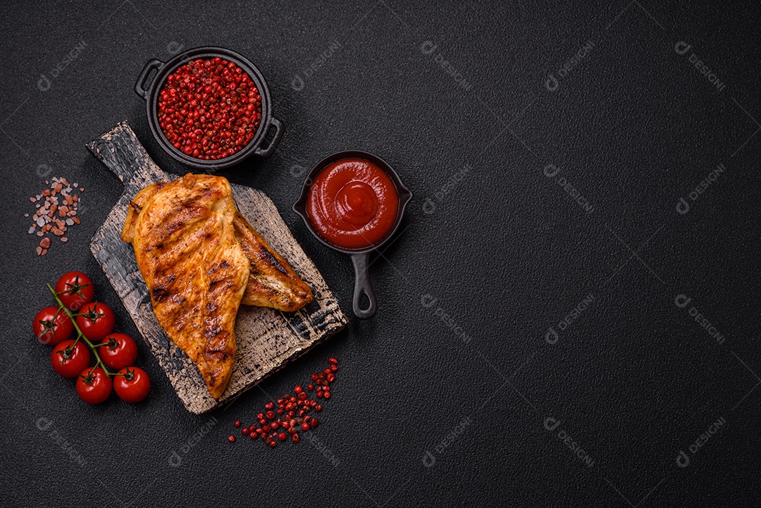Delicioso filé de frango grelhado fresco com especiarias e ervas em um fundo escuro de concreto. Um prato cozido no fogo