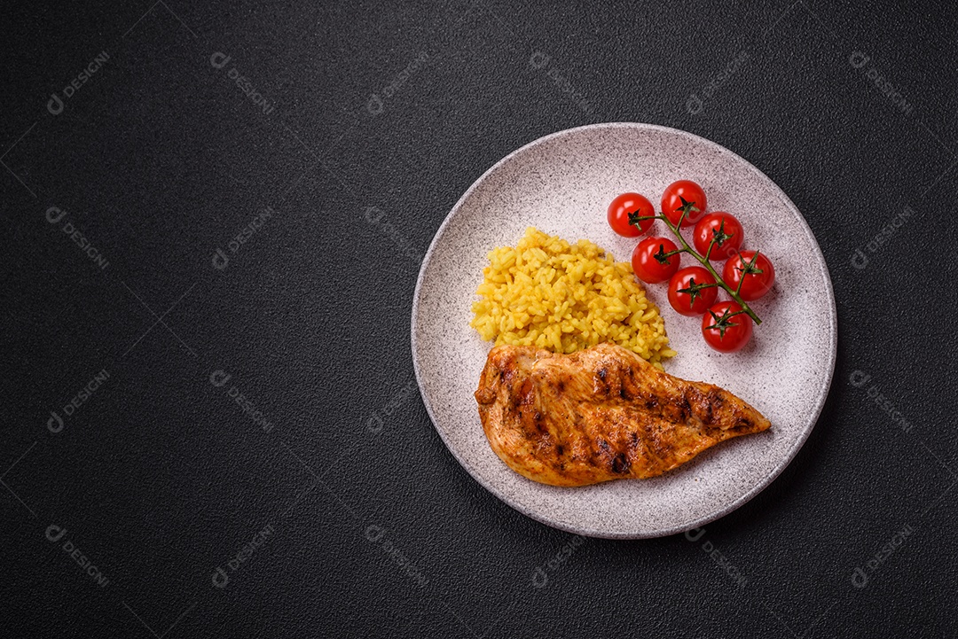 Delicioso filé de frango grelhado fresco com especiarias e ervas em um fundo escuro de concreto. Um prato cozido no fogo