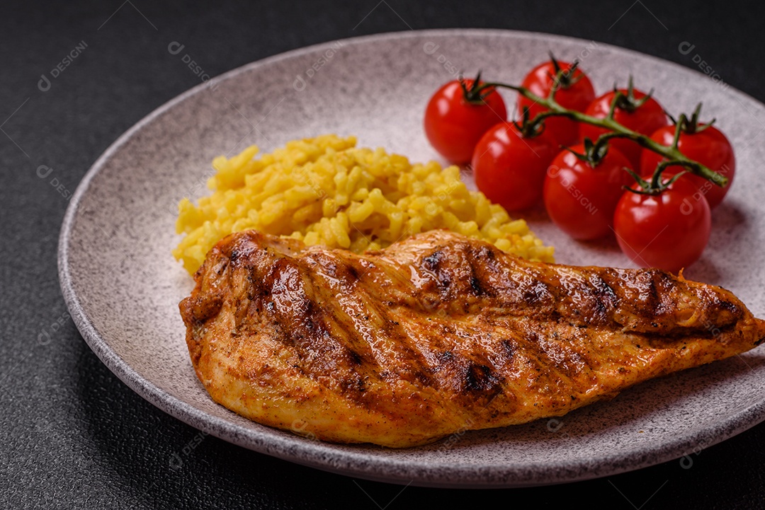 Delicioso filé de frango grelhado fresco com especiarias e ervas em um fundo escuro de concreto. Um prato cozido no fogo