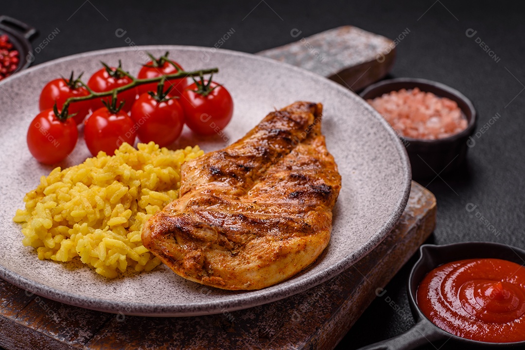 Delicioso filé de frango grelhado fresco com especiarias e ervas em um fundo escuro de concreto. Um prato cozido no fogo