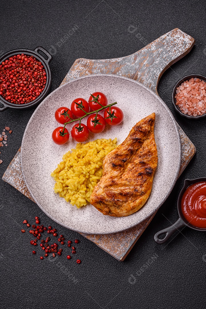 Delicioso filé de frango grelhado fresco com especiarias e ervas em um fundo escuro de concreto. Um prato cozido no fogo