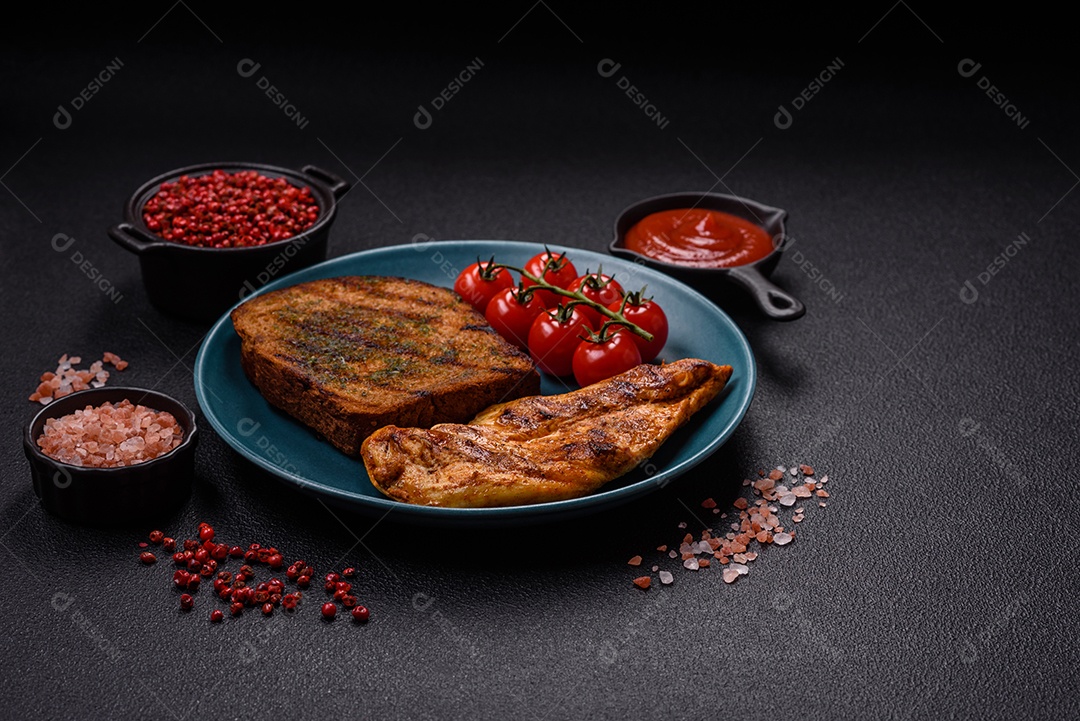 Delicioso filé de frango grelhado fresco com especiarias e ervas em um fundo escuro de concreto. Um prato cozido no fogo