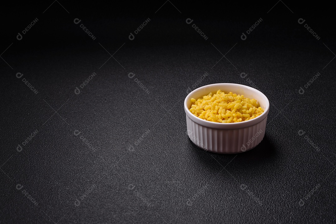 Delicioso arroz amarelo cozido com açafrão, sal e especiarias sobre um fundo escuro de concreto