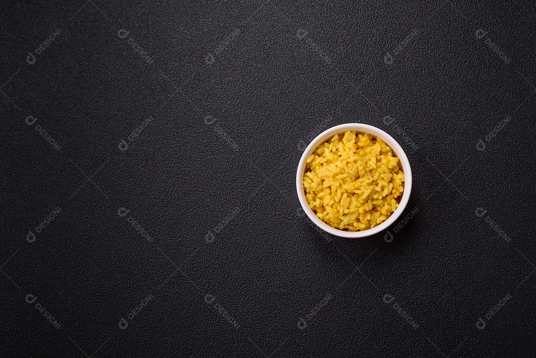 Delicioso arroz amarelo cozido com açafrão, sal e especiarias sobre um fundo escuro de concreto