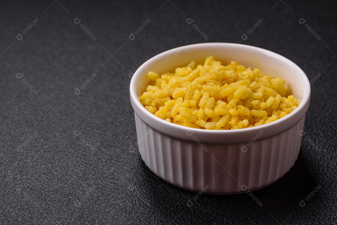 Delicioso arroz amarelo cozido com açafrão, sal e especiarias sobre um fundo escuro de concreto