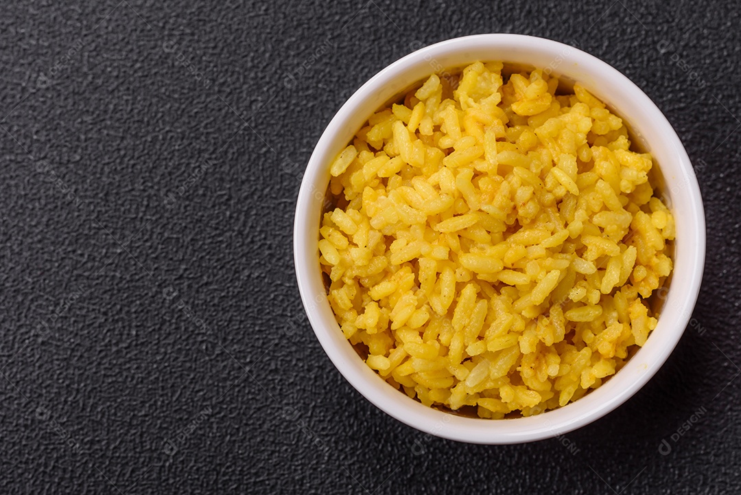 Delicioso arroz amarelo cozido com açafrão, sal e especiarias sobre um fundo escuro de concreto