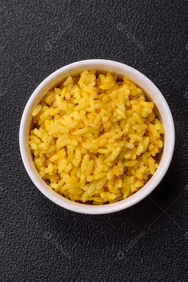 Delicioso arroz amarelo cozido com açafrão, sal e especiarias sobre um fundo escuro de concreto