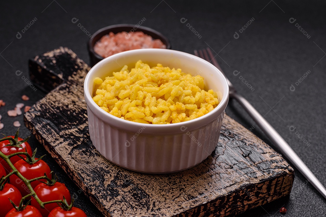 Delicioso arroz amarelo cozido com açafrão, sal e especiarias sobre um fundo escuro de concreto