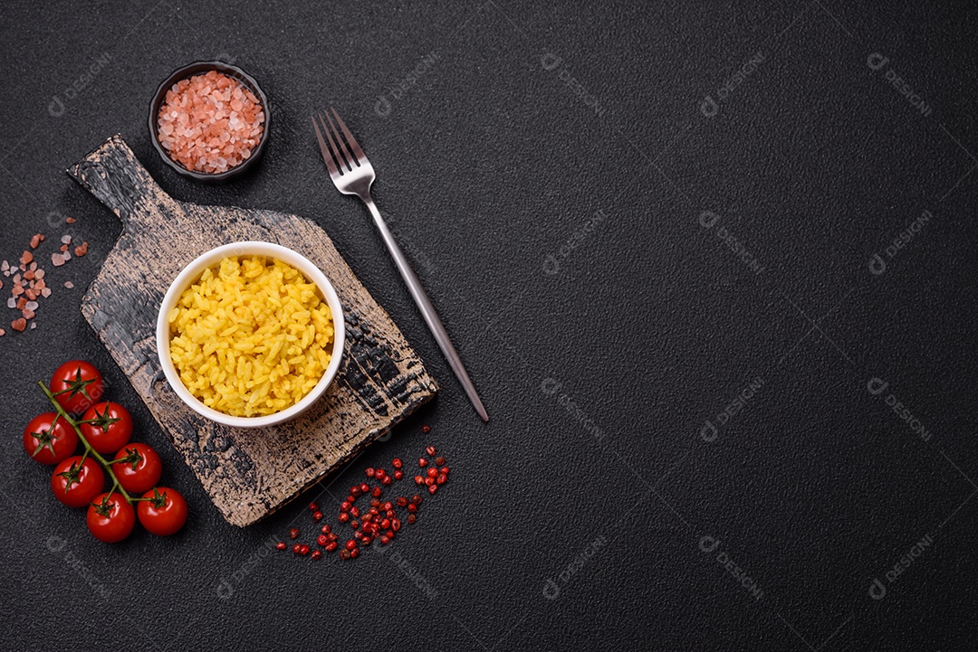 Delicioso arroz amarelo cozido com açafrão, sal e especiarias sobre um fundo escuro de concreto